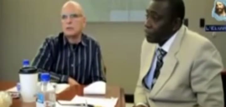 Joseph Branham (left), president of Voice of God Recordings, speaking on camera in a 2017 video uploaded to VGR's own YouTube channel. He is seated next to Pastor Kamté.